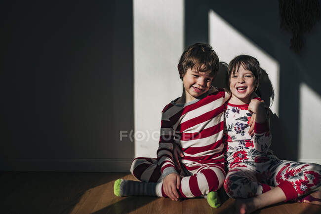 Мальчик и девочка сидят на полу и обнимаются — стоковое фото