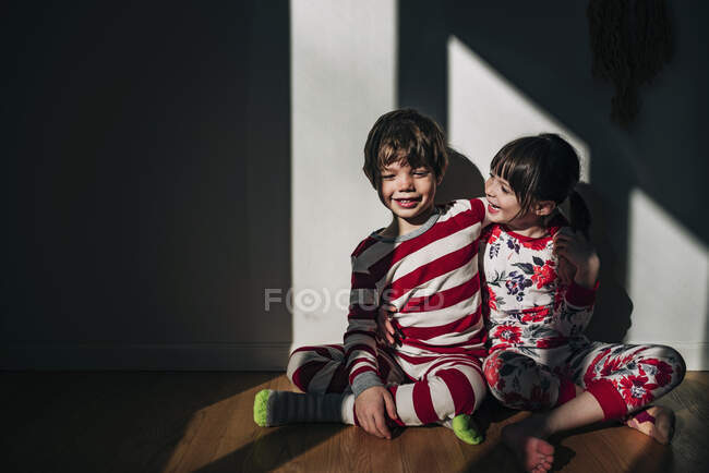 Boy and girl sitting on floor hugging — Stock Photo