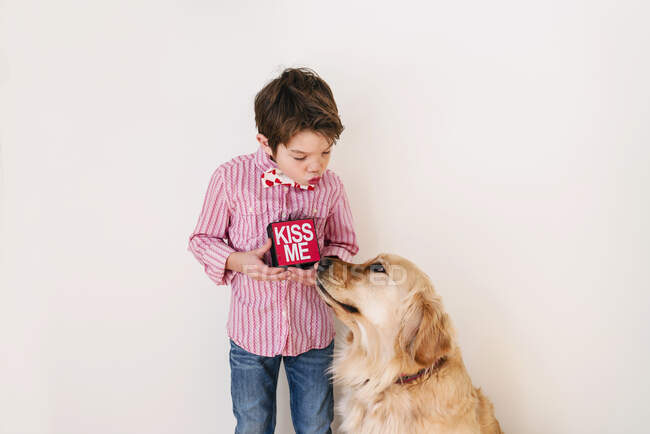 Ragazzo soffiando un bacio al suo cane golden retriever — Foto stock