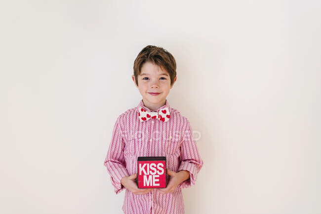 Smiling boy holding a Kiss me box — Stock Photo