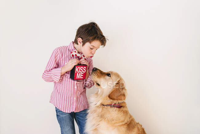 Chico soplando un beso a su perro golden retriever - foto de stock