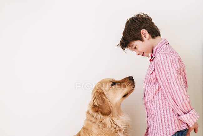 Chico mirando a su perro golden retriever - foto de stock