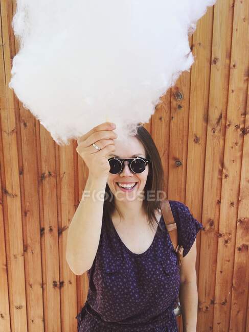Retrato de una mujer sonriente sosteniendo algodón de azúcar - foto de stock