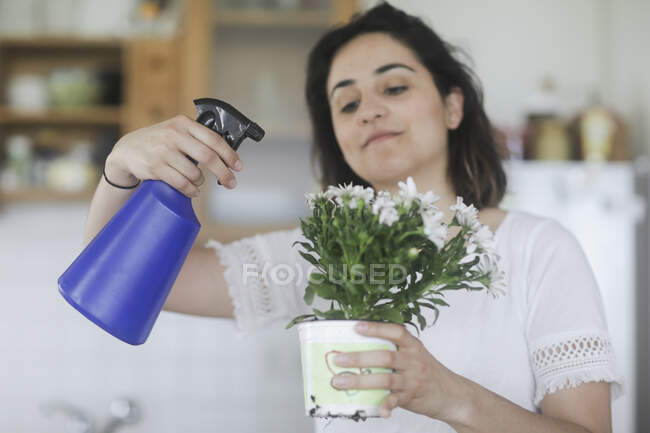 Woman spraying flowers with water — Stock Photo