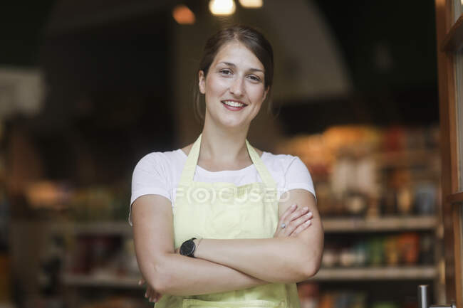 Retrato de una asistente de ventas sonriente con los brazos cruzados - foto de stock