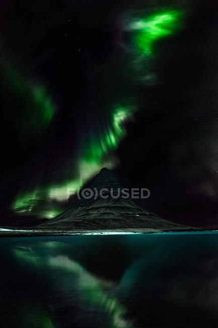 Vista panorámica de las luces boreales sobre la montaña Kirkjufell, región noroeste, Islandia - foto de stock