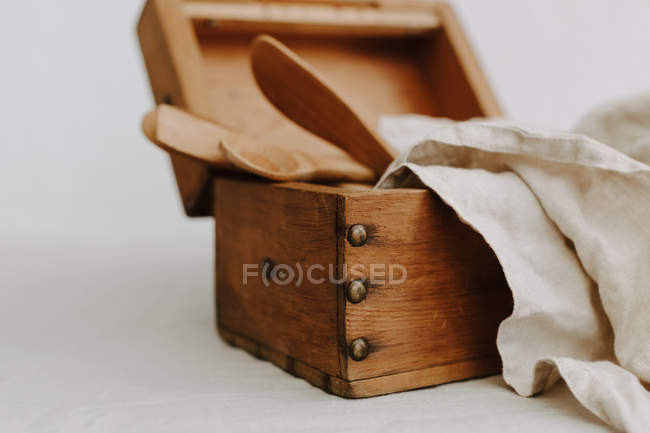 Caja de madera con utensilios de cocina y servilletas de lino. - foto de stock