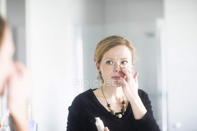 Femme debout dans la salle de bain appliquant maquillage — Photo de stock