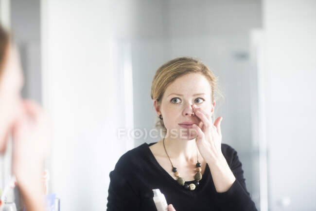 Mulher de pé no banheiro aplicando maquiagem — Fotografia de Stock