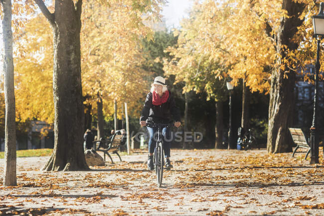 Woman cycling through a park in the autumn, Germany — Stock Photo