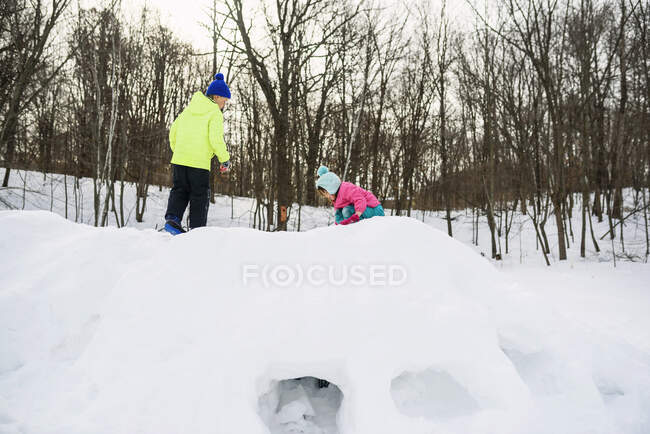 Niño y niña construyendo un fuerte de nieve - foto de stock