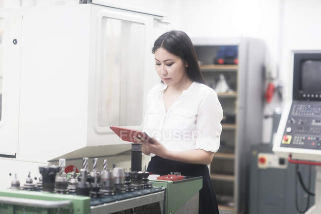 Portrait of a female engineer standing in a workshop holding a digital tablet — Stock Photo