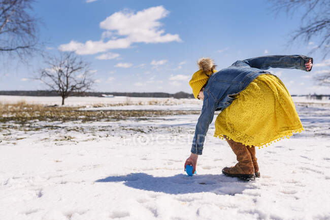 Chica en una búsqueda de huevos de Pascua en la nieve - foto de stock