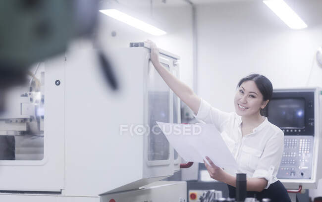 Smiling female engineer looking at a technical drawing — Stock Photo