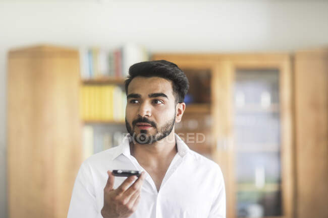 Man standing in the living room talking on his mobile phone — Stock Photo