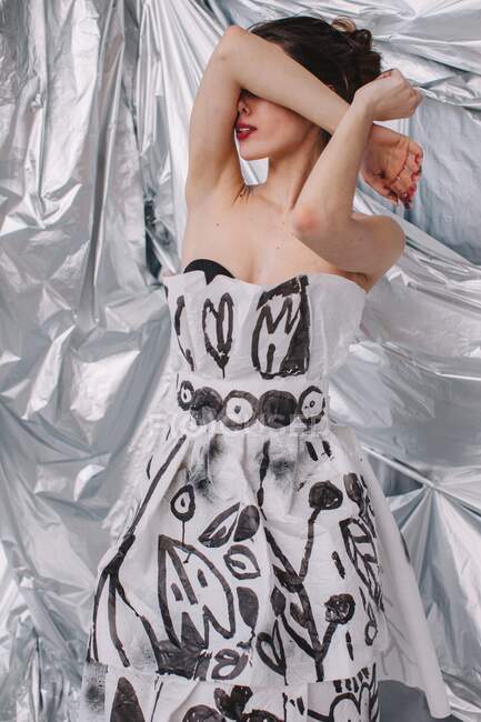 Porträt einer Frau in einem Papierkleid, deren Arme ihr Gesicht bedecken — Stockfoto
