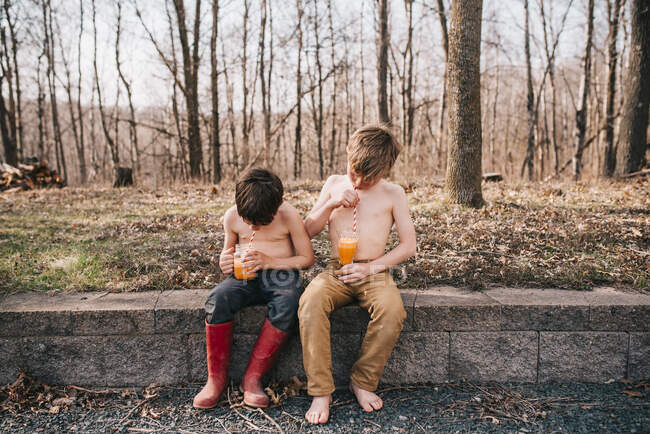 Two boys sitting on a wall enjoying a summer drink — Stock Photo