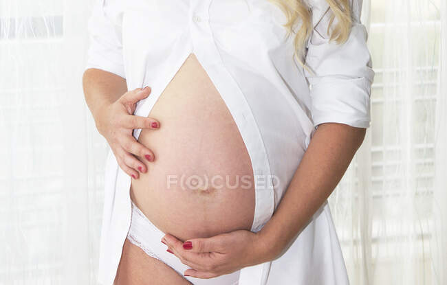 Mujer embarazada acunando su bulto - foto de stock
