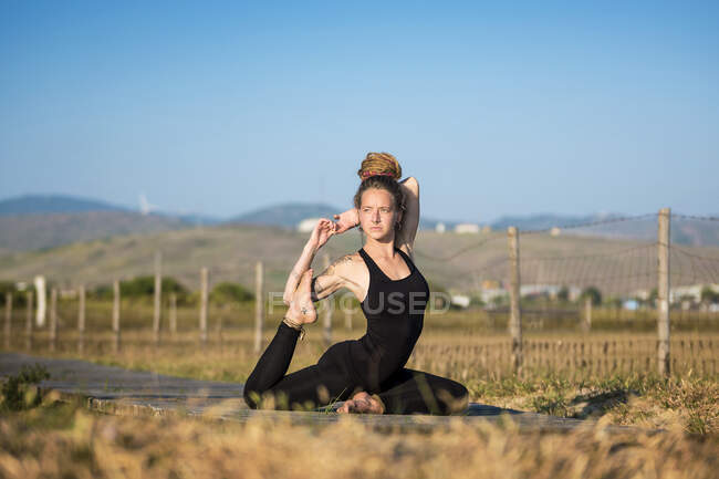 Donna che fa yoga mezza posa di piccione, Parco Naturale dello Stretto, Tarifa, Cadice, Andalusia, Spagna — Foto stock