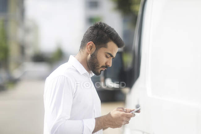 Man standing in the street checking his mobile phone — Stock Photo