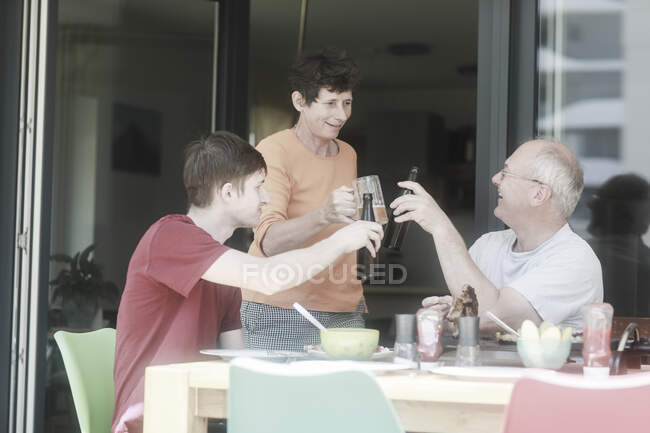 Familia almorzando, haciendo un brindis de celebración - foto de stock