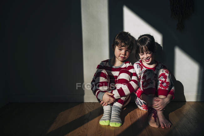 Frère et sœur assis par terre en pyjama — Photo de stock
