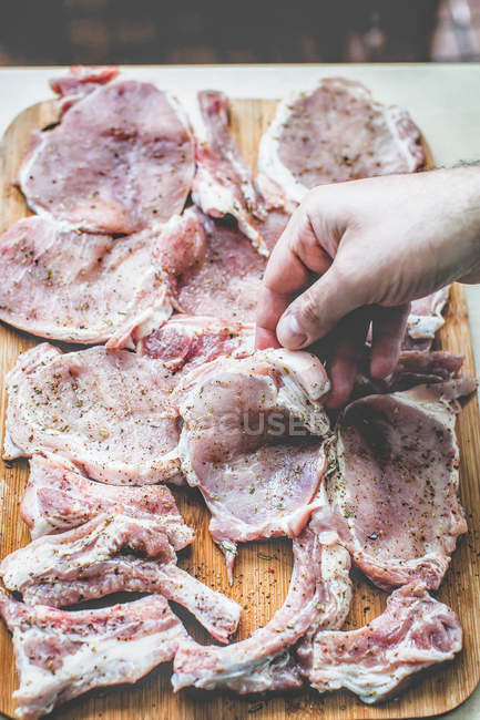 Human hand preparing raw pork steaks, closeup view — Stock Photo