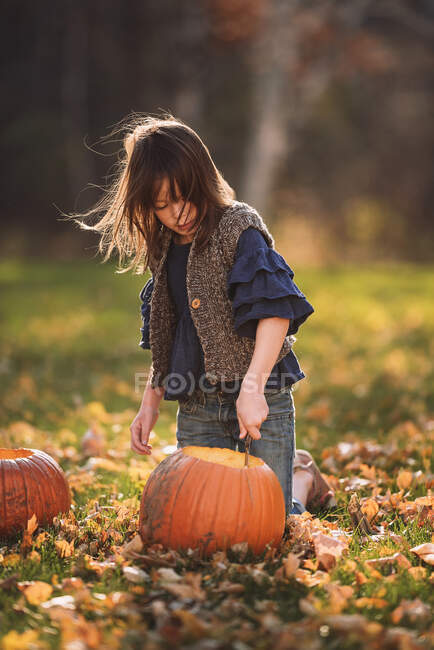 Ragazza che intaglia una zucca di Halloween in giardino, Stati Uniti — Foto stock