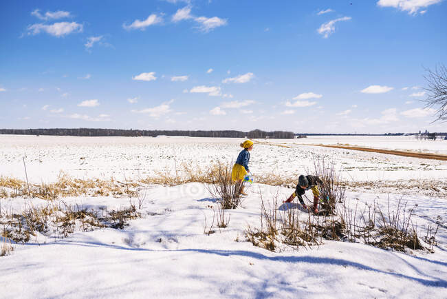 Garçon et fille sur une chasse aux œufs de Pâques dans la neige — Photo de stock