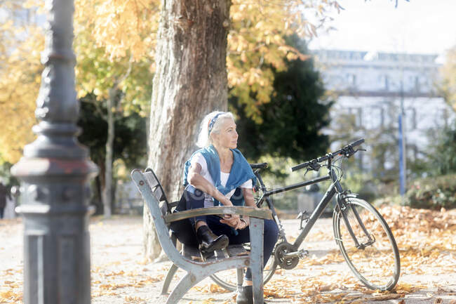 Frau sitzt im Park auf einer Bank — Stockfoto