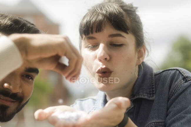Couple souriant soufflant une poignée de confettis — Photo de stock