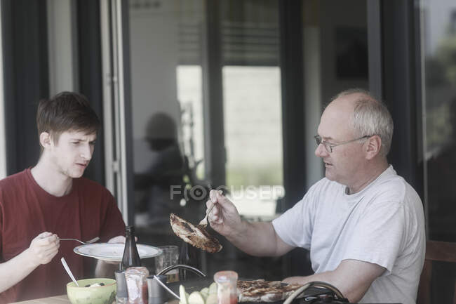 Adulto pai servindo churrasco bife para seu filho — Fotografia de Stock