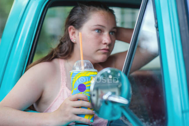 Дівчинка сидить у вантажівці з випивкою в одноразовій чашці. — стокове фото