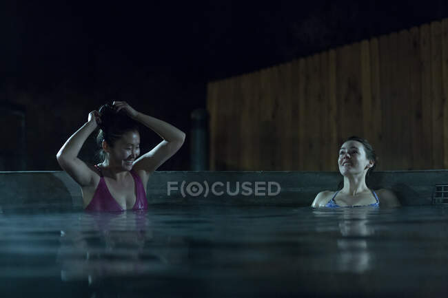 Two women in a swimming pool at night — Stock Photo