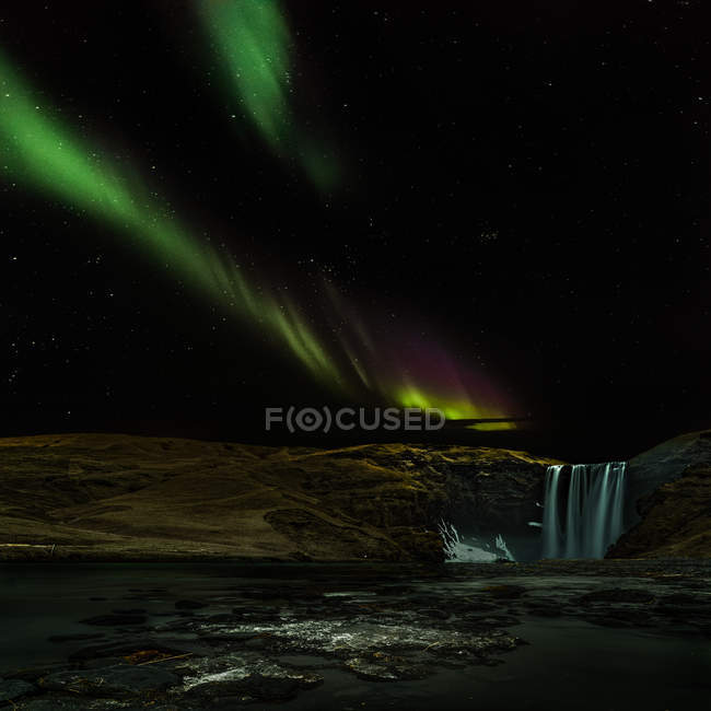 Vue panoramique des aurores boréales sur la cascade de Skogarfoss, région du Sud, Islande — Photo de stock