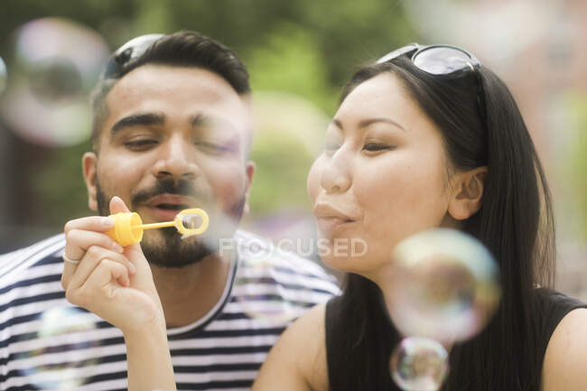 Пара тримає бульбашкову паличку, що дме мильні бульбашки — стокове фото