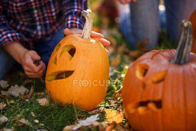 Brother and sister sitting in the garden carving Halloween pumpkins, United States — Stock Photo