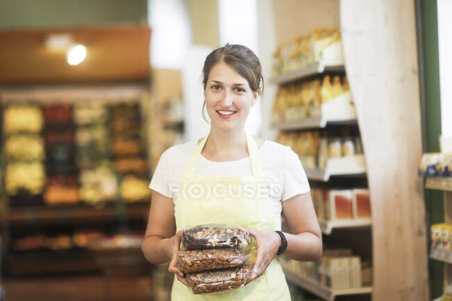 Smiling sales assistant holding bags of nuts — Stock Photo