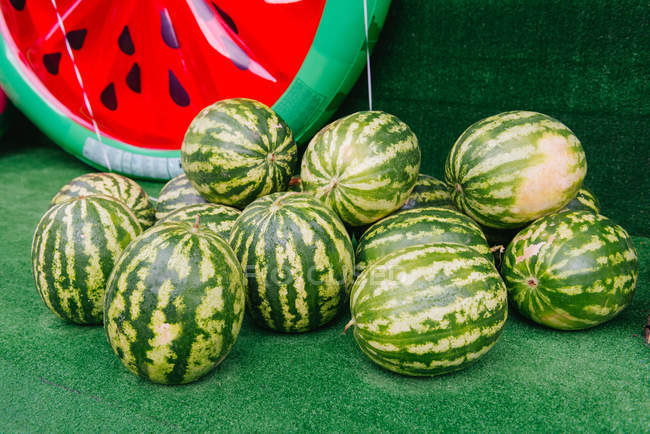 Pilha de melancias ao lado de uma melancia inflável — Fotografia de Stock