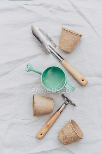 El riego puede, herramientas de jardinería y macetas de flores en manteles de lino. - foto de stock