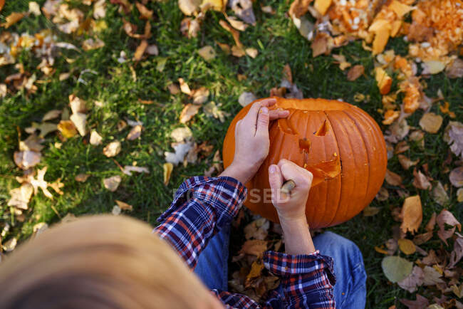 Хлопчик, який вирізьблює Хелловін гарбуза в саду (США). — стокове фото