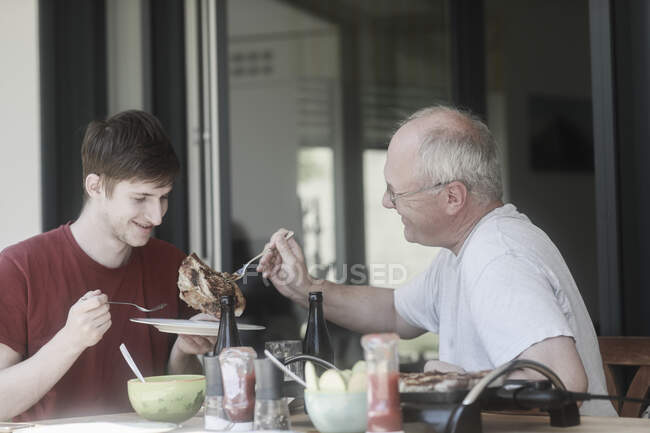 Adult father serving barbecued steak to his son — Stock Photo