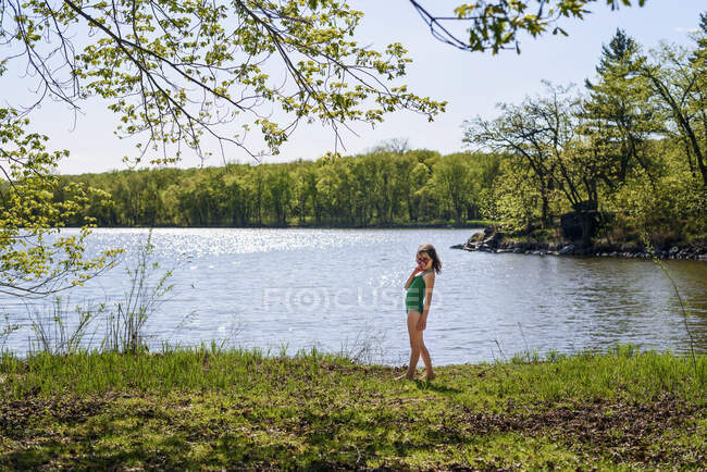 Fille debout près d'un lac dans son costume de natation — Photo de stock