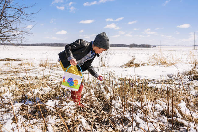 Boy on an Easter egg hunt in the snow — Stock Photo
