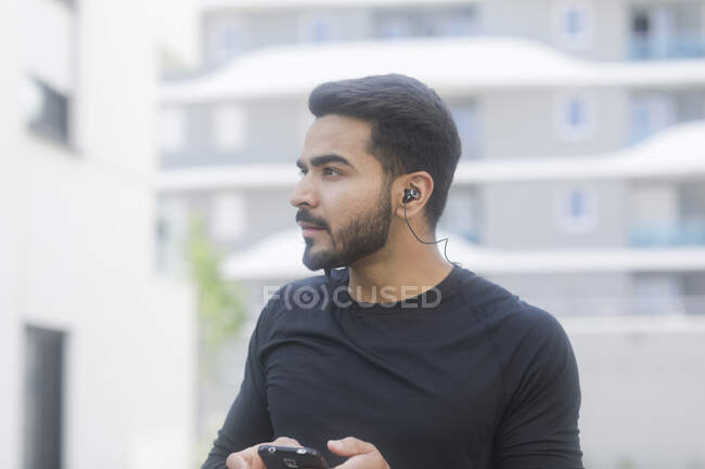 Hombre escuchando música en su smartphone mientras trota - foto de stock