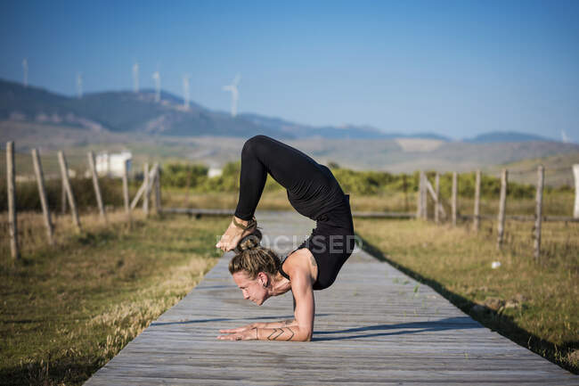 Mulher fazendo uma pose de escorpião ioga, O Estreito Parque Natural, Tarifa, Cádiz, Andaluzia, Espanha — Fotografia de Stock