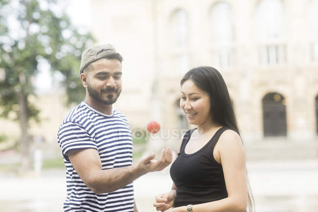 Couple standing in a city square playing with a ball — Stock Photo