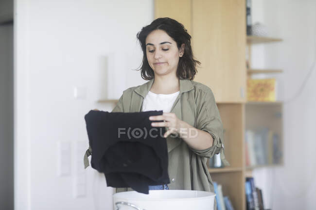 Woman standing in the utility room folding clothing — Stock Photo