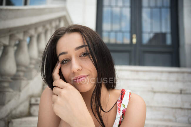 Портрет улыбающейся женщины, сидящей на ступеньках перед зданием — стоковое фото