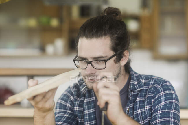 Man standing in kitchen holding a homemade chopping board — Stock Photo